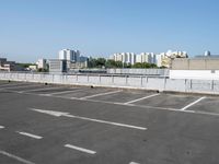 an empty parking lot with multiple cars parked in it in front of the city skyline