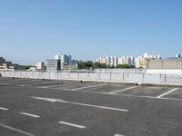 an empty parking lot with multiple cars parked in it in front of the city skyline