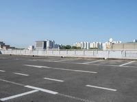 an empty parking lot with multiple cars parked in it in front of the city skyline