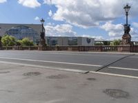 a person riding their bike across a bridge in front of buildings and blue sky with clouds