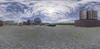 a view of a road and buildings with cloudy skies in the background while fisheye lens is done