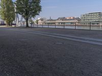 a bench with a bag on it near the water and city buildings in the background