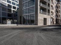 an empty city street with an intersection sign and graffiti on the side of the building