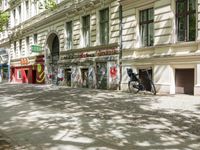 a restaurant in the middle of a narrow city street with graffiti on the wall and the sidewalk outside the building