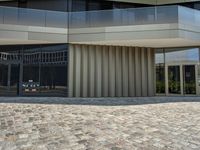 some people walking a dog on the stone pavement outside a building that looks like a hotel