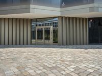 some people walking a dog on the stone pavement outside a building that looks like a hotel