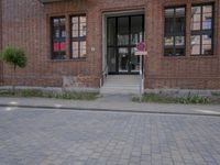 a stop sign sits near a red brick building with stairs and windows that are closed