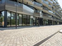 a building with many windows on top of it and cobblestone outside of them