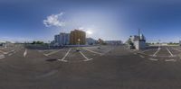 a parking lot with parking spaces in the foreground and buildings and blue skies in the background