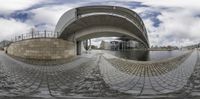 a view through the fisheyes of a bridge with buildings in the background next to water