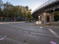 a crosswalk going under a bridge over a road with graffiti on the ground and signs painted on it