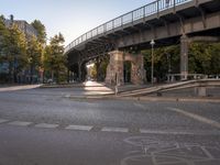 a crosswalk going under a bridge over a road with graffiti on the ground and signs painted on it