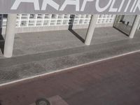 a view of a sidewalk with several pillars and a building in the background with text on it