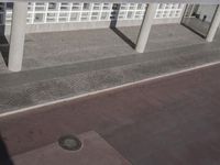 a view of a sidewalk with several pillars and a building in the background with text on it