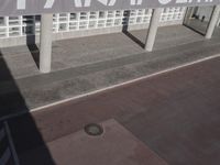 a view of a sidewalk with several pillars and a building in the background with text on it