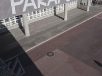 a view of a sidewalk with several pillars and a building in the background with text on it