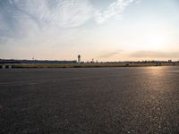 a man flying a kite on top of a large tarmac in an airport setting