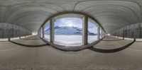 a fish eye view of the road going up to the mountains from the top of a large, curving snow - covered hill