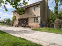 a brown house with a picnic table and bench in front of it next to a road