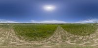 a camera view of an open field with grass and a blue sky in the background