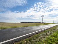 a view of a road that has a pole on it in the distance, with the sky in the background