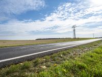 a view of a road that has a pole on it in the distance, with the sky in the background