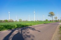 the sun is shining on a rural road by wind turbines from across the country side