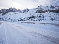 a snow covered mountain road with rocks in the distance and a bench on the right side