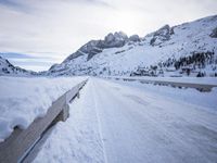 a snow covered mountain road with rocks in the distance and a bench on the right side