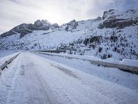 a snow covered mountain road with rocks in the distance and a bench on the right side