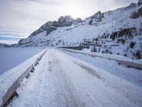 a snow covered mountain road with rocks in the distance and a bench on the right side