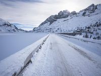 a snow covered mountain road with rocks in the distance and a bench on the right side