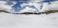 a snow covered ski slope with a skiier skiing on it with trees and mountains in the distance