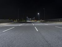 the empty highway is lit up at night time near a stadium or stadium complex with lights