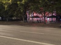 a street with a restaurant next to it at night time by the curb of a road