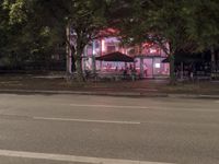 a street with a restaurant next to it at night time by the curb of a road
