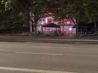 a street with a restaurant next to it at night time by the curb of a road