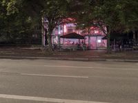 a street with a restaurant next to it at night time by the curb of a road