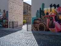 street scene with brick walkway next to graffiti art on building walls and metal gate and outdoor seating