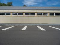 a metal building with a corrugated door in front of it and trees lining the street behind it