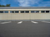 a metal building with a corrugated door in front of it and trees lining the street behind it