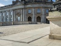 an elegant building with a bronze head in front of it and two statues in the foreground