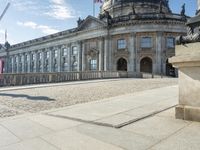 an elegant building with a bronze head in front of it and two statues in the foreground