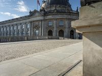 an elegant building with a bronze head in front of it and two statues in the foreground