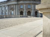 an elegant building with a bronze head in front of it and two statues in the foreground