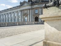 an elegant building with a bronze head in front of it and two statues in the foreground