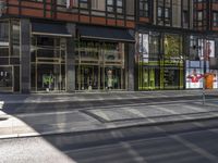 an empty street with some buildings around it and windows in the front, reflecting the sun and the surrounding