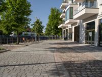 a paved courtyard in front of an office building near a park filled with benches and trees