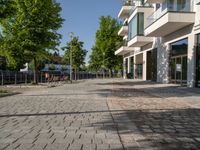 a paved courtyard in front of an office building near a park filled with benches and trees