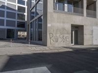 some graffiti has been written on the side of a building across from a parking lot